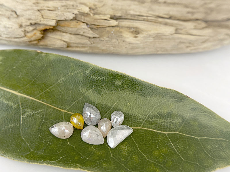 A tray of sapphires and diamonds under soft side light, showing color and cut differences